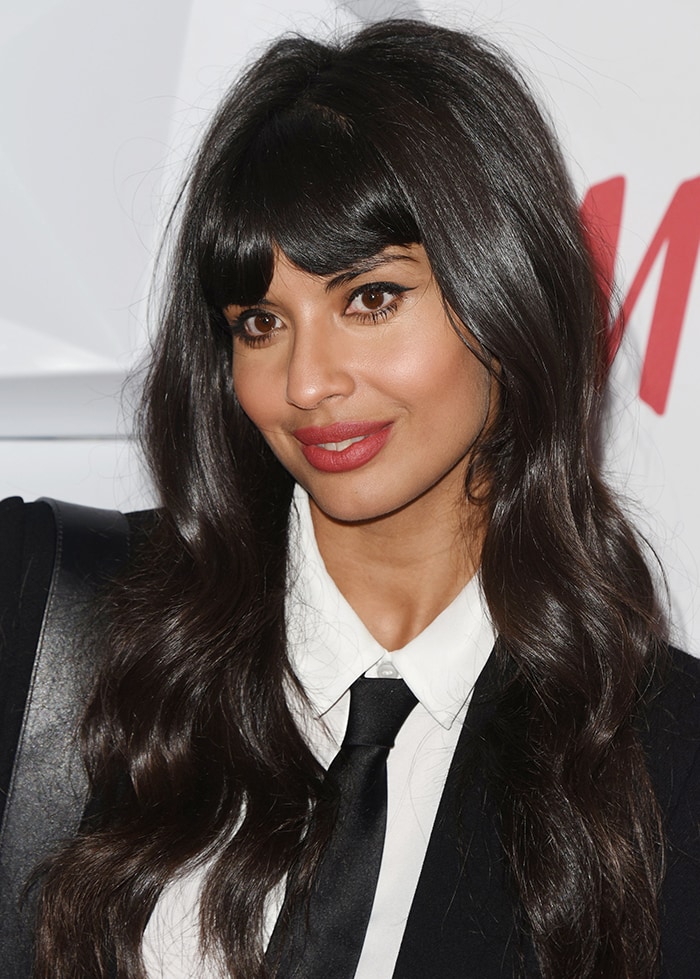 Jameela Jamil wears red lipstick and dark eye make-up, and styles her long black fringe hair in soft waves 