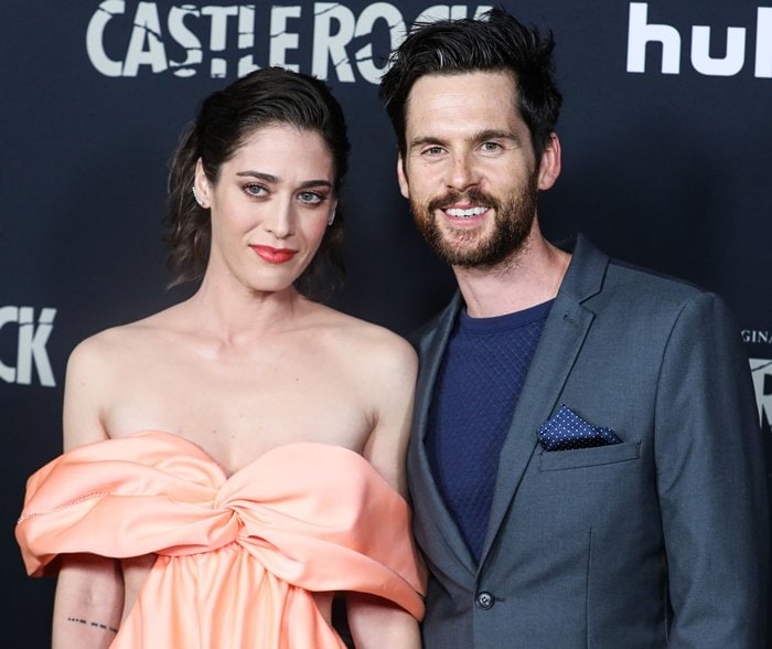 Lizzy Caplan and Tom Riley attend the Castle Rock season two premiere, with Lizzy wearing a peach off-the-shoulder gown and Tom in a sharp gray suit