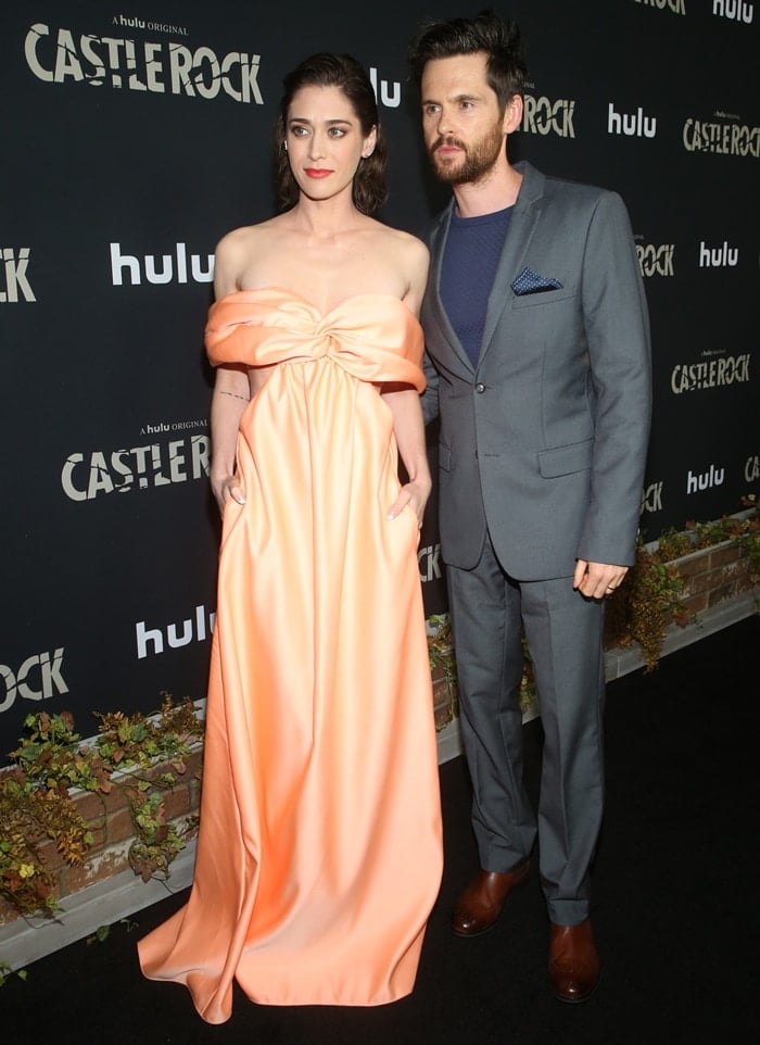 Lizzy Caplan stuns in a peach off-the-shoulder gown alongside husband Tom Riley at the Castle Rock season two premiere in Los Angeles