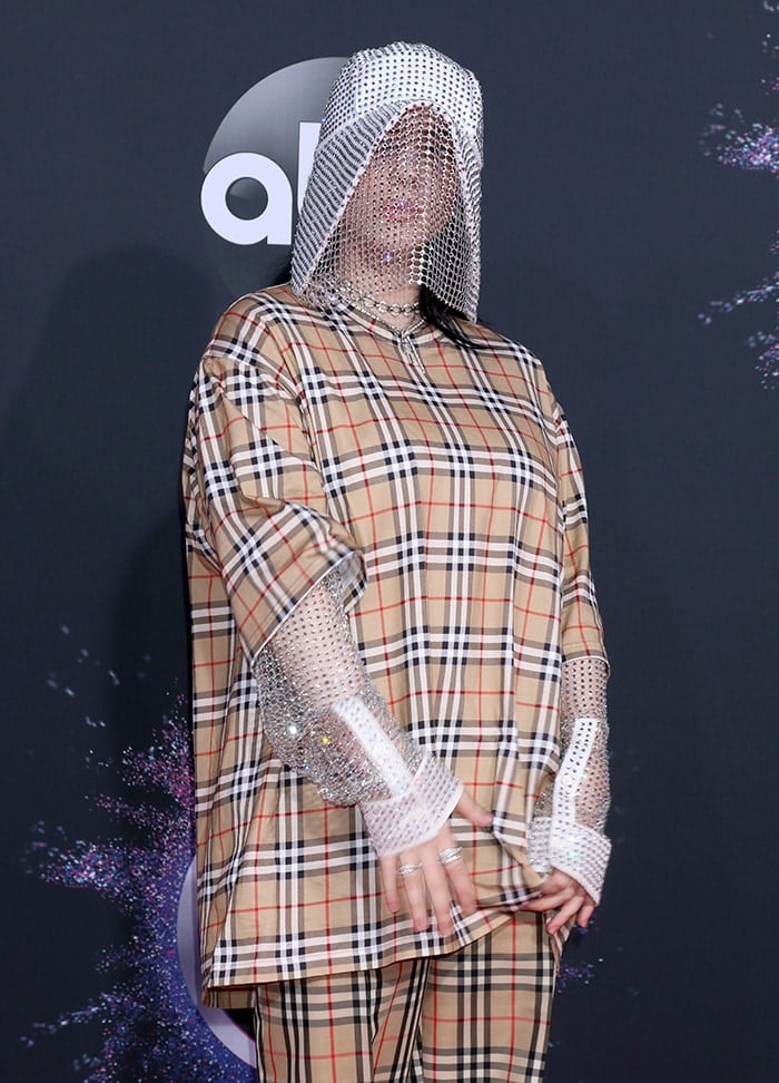 Billie Eilish's head-to-toe Burberry ensemble featured a distinctive touch with a custom beekeeper hat by the design house, covering her face and adding an edgy flair to her red carpet appearance