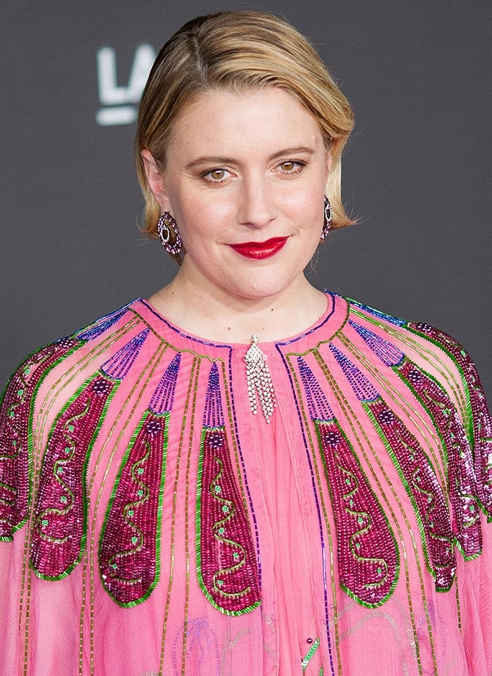 Greta Gerwig sports a slicked side-parted hairstyle with bold red lipstick