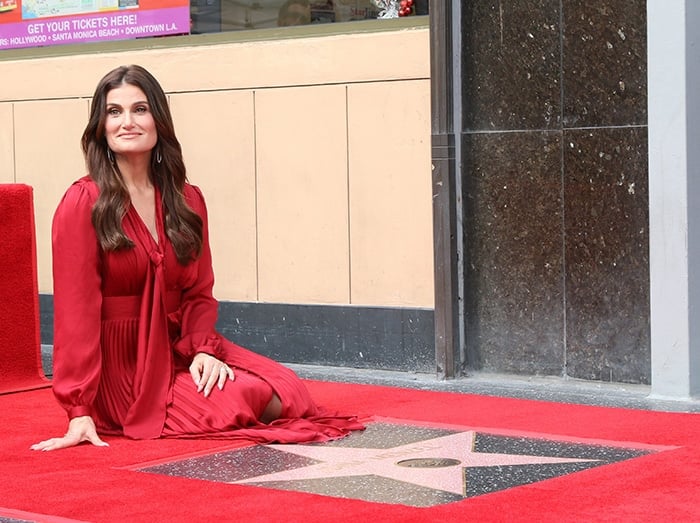 Idina Menzel wears soft makeup with her tresses styled in voluminous waves over her shoulders