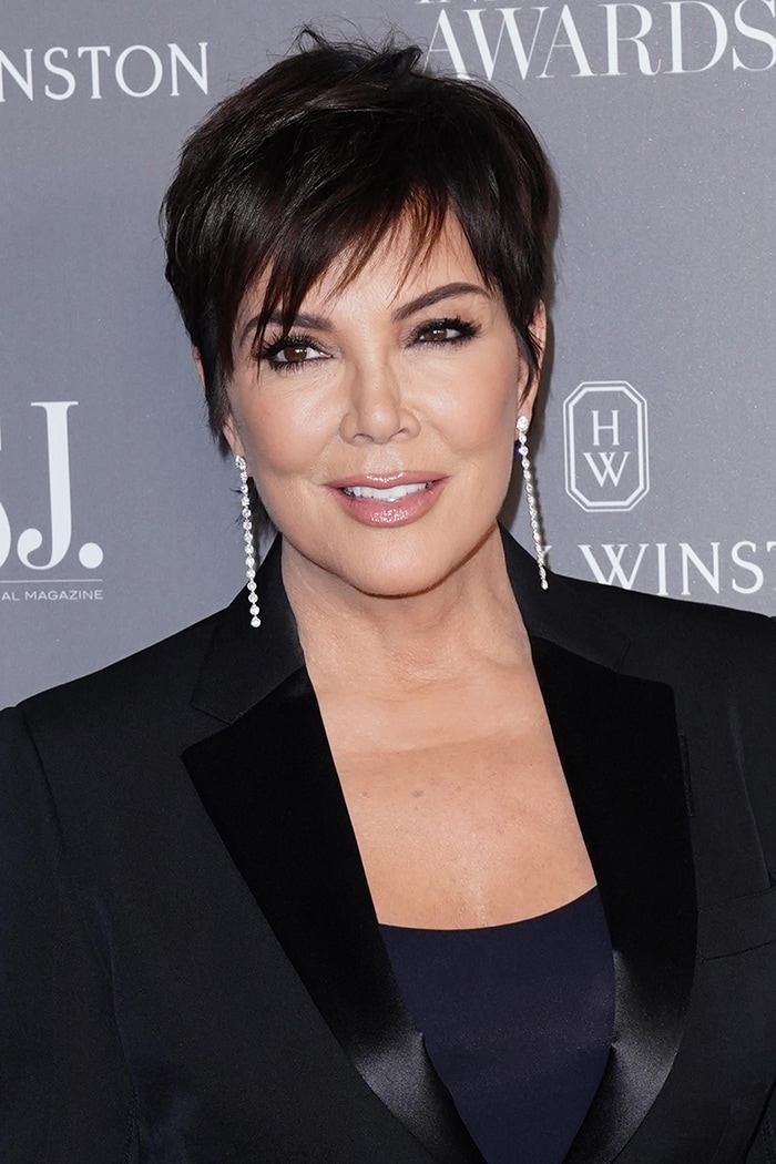 Kris Jenner wears mussed pixie haircut and dark eyeliner, mascara, and nude lipgloss