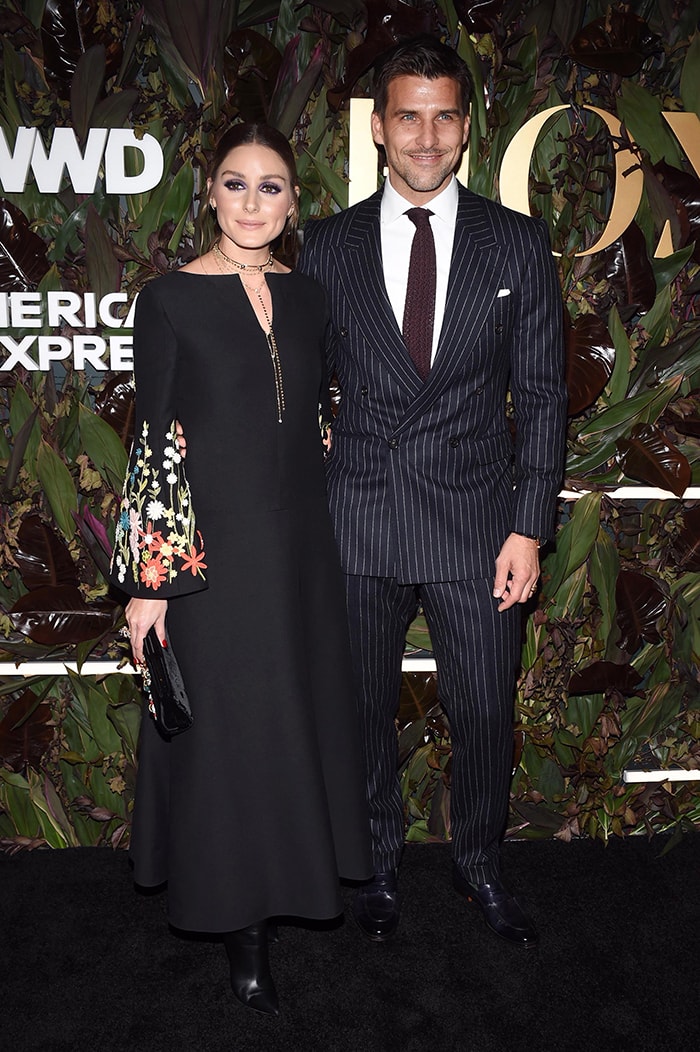 Olivia Palermo poses with her husband Johannes Huebl on the WWD Honors black carpet