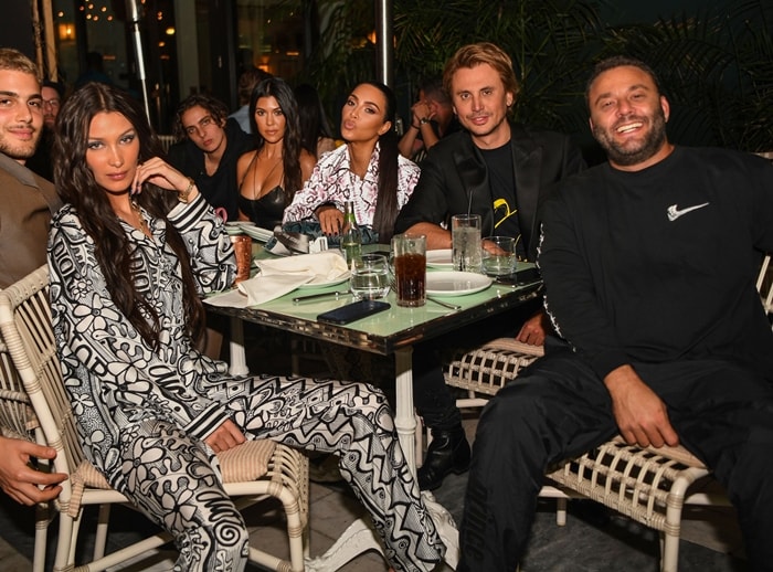 LIV nightclub owner David Grutman smiling with Bella Hadid, Kourtney Kardashian, Jonathan Foodgod Cheban, and Bad Bunny are seen at Swan