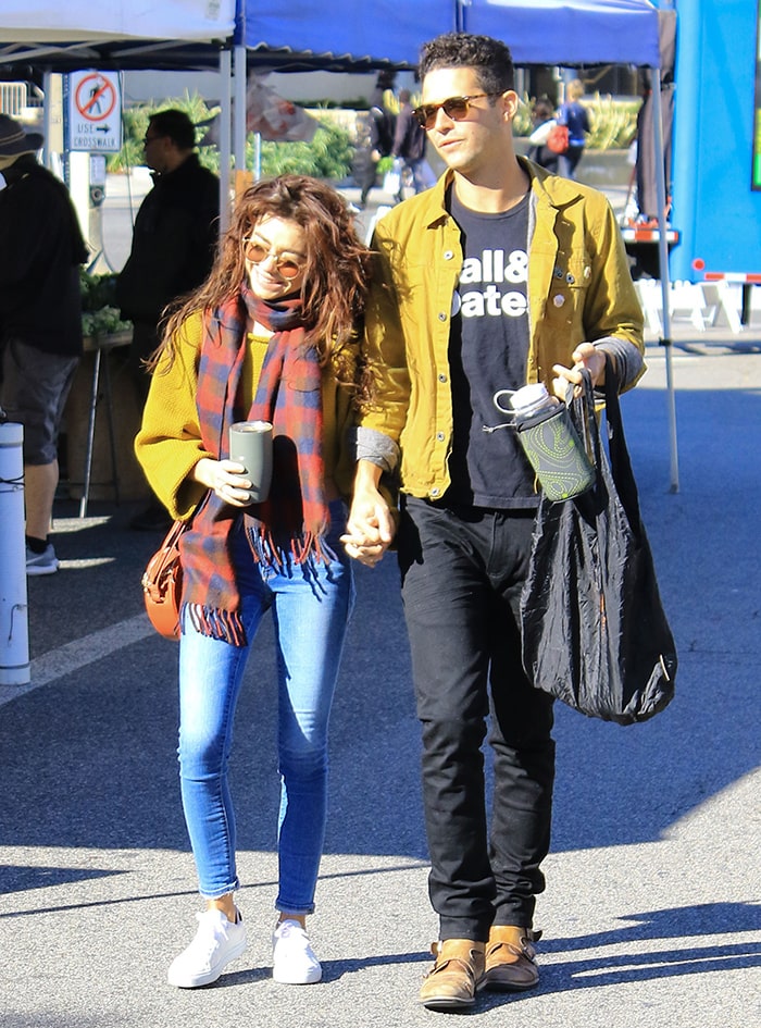 Sarah Hyland and Wells Adams walk arm-in-arm at a Los Angeles farmer's market on December 15, 2019