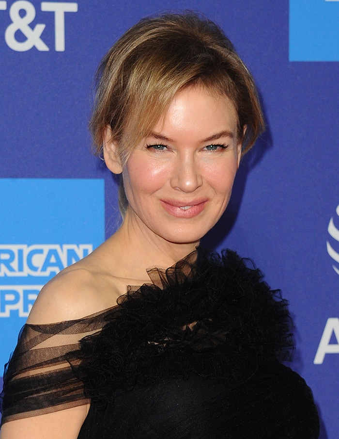 Renée Zellweger wears a loose ponytail with soft pink makeup