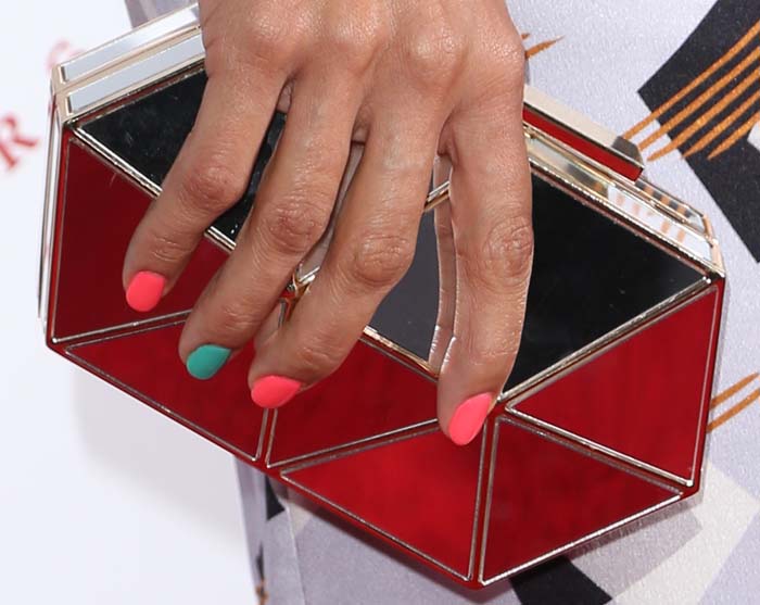 Rosario Dawson adds a playful pop of color to her geometric Vince Camuto “Aleni” clutch with bright coral and mint nail