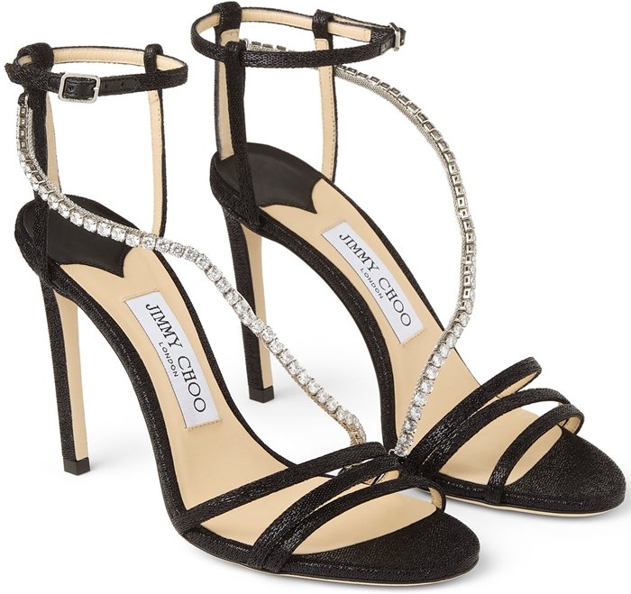 Delicate stiletto sandals featuring a languid, crystal-embellished strap that curves over the foot