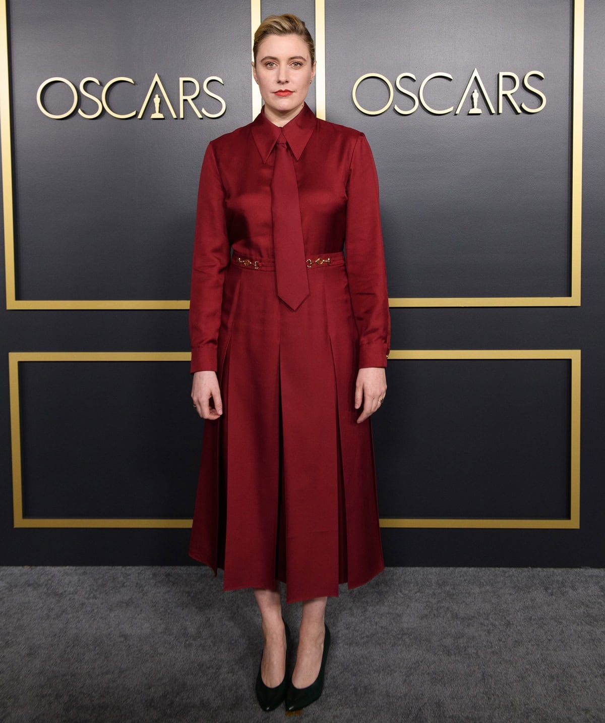 Greta Gerwig gives classic menswear a feminine spin in a berry-red Gucci shirtdress with a matching tie and forest-green heels at the 2020 Oscars Nominees Luncheon in Hollywood