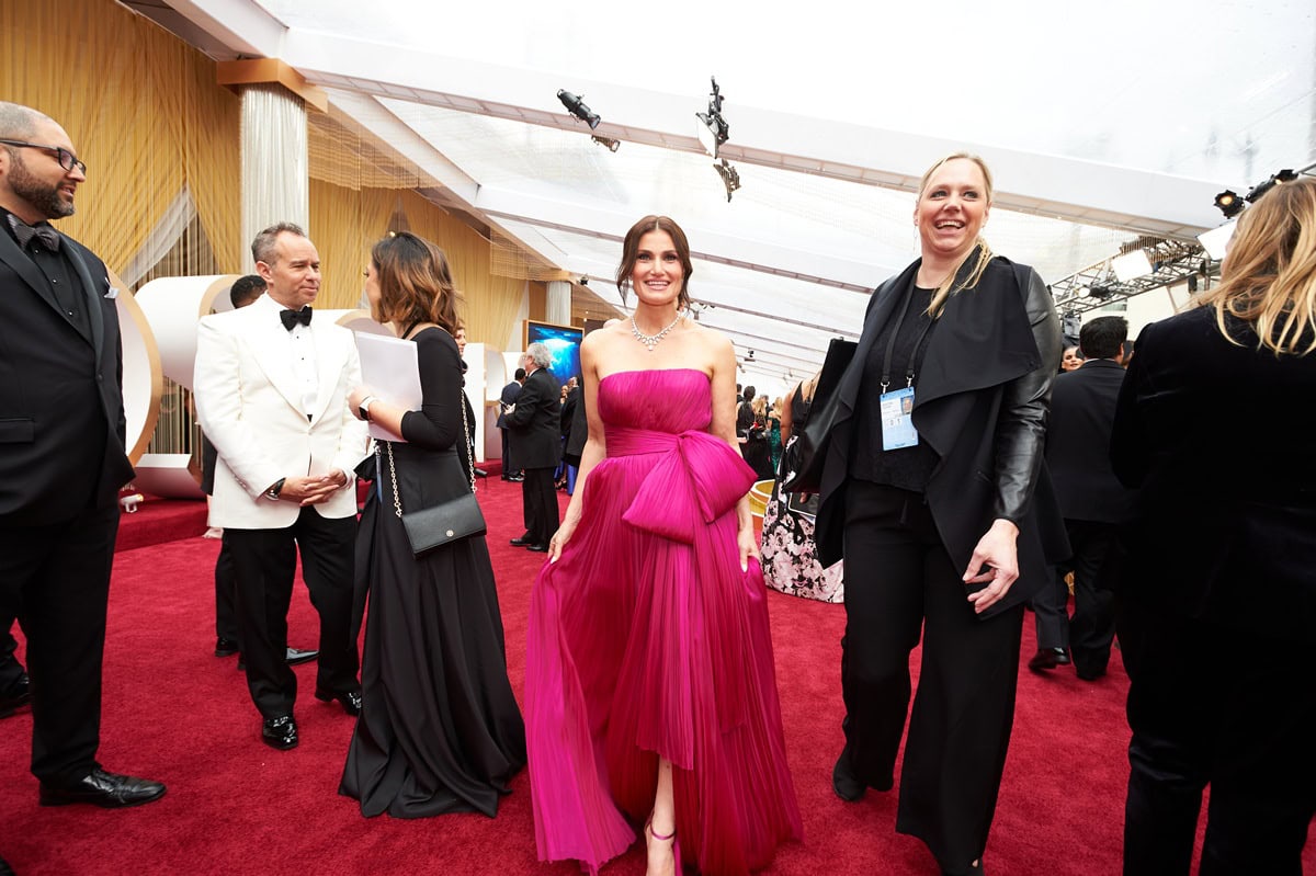 Idina Menzel lit up the 2020 Oscars red carpet in a custom magenta J. Mendel gown with a dramatic bow detail, paired with metallic Malone Souliers sandals and Harry Winston diamond jewelry