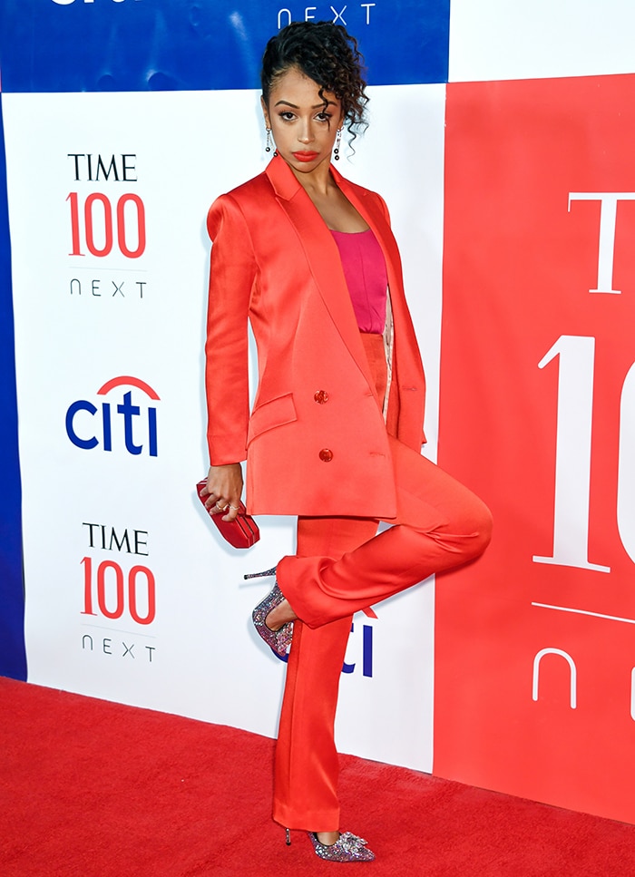 Liza Koshy in a red pantsuit and glittery pumps at the Time 100 Next List red carpet