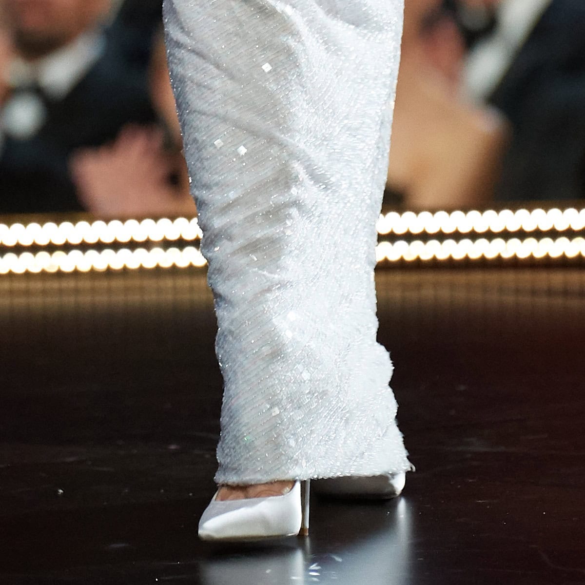 Zellweger’s look was grounded by sleek white Jimmy Choo pointed-toe pumps, their clean satin finish and sculpted stiletto heel echoing the gown’s refined, minimalist sparkle