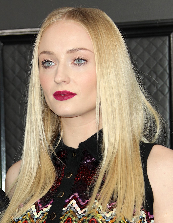 Sophie Turner opts for glam goth with bold fuchsia lipstick and center-parted straightened hair