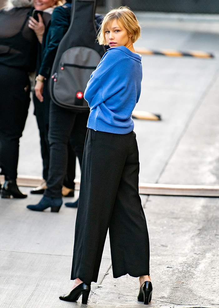 Grace VanderWaal in a blue sweater and loose-fitting black trousers outside the studio