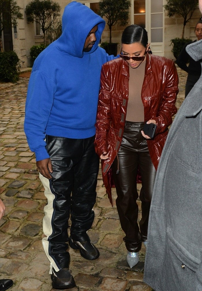 Wearing a brick red trench coat, Kim Kardashian West is seen with her husband Kanye West