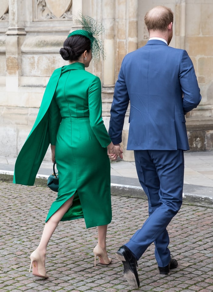 Meghan Markle wore a green pleated midi dress featuring a band collar, a button fastening, a fitted waist, long sleeves, a straight hem, and a back zip fastening