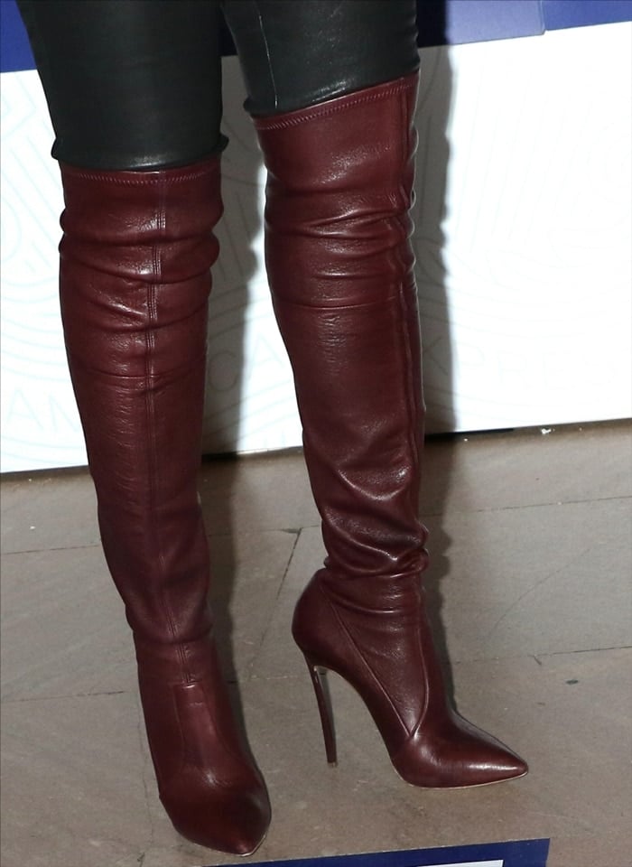 Taraji P. Henson elevates her look in towering burgundy leather over-the-knee boots by Casadei, featuring a sharp pointed toe and stiletto heel that create a sleek, leg-lengthening effect