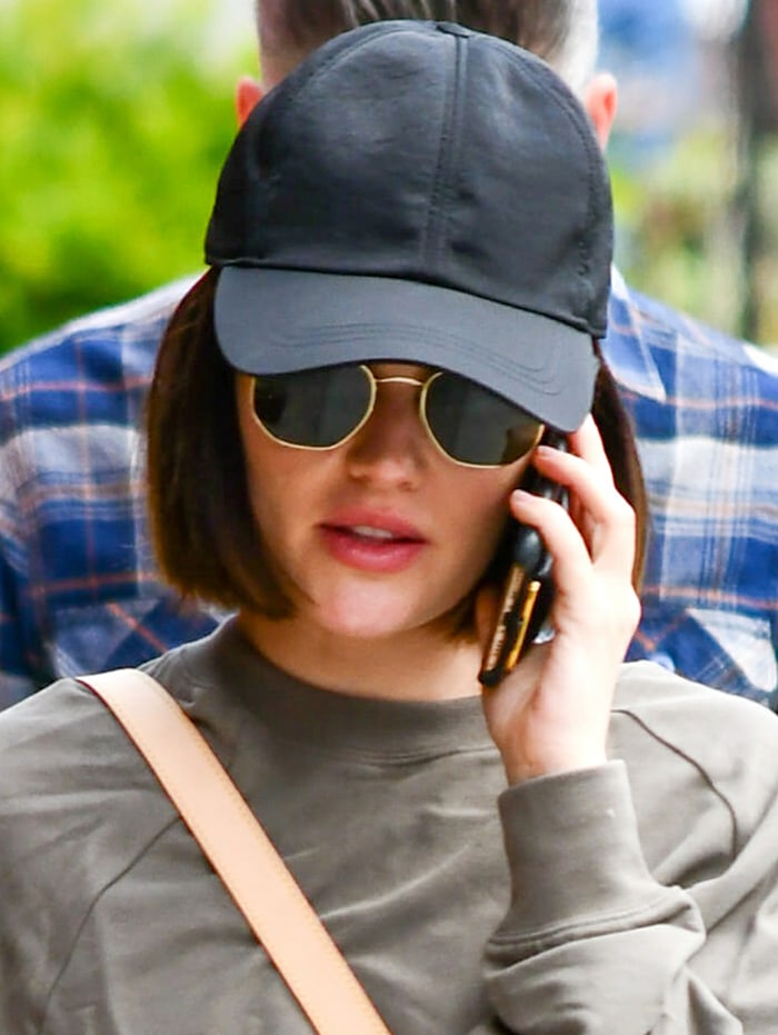 Lucy Hale keeps things low-key with sunglasses and a black cap