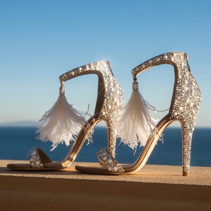 An ostrich-feather tassel adds an ethereal touch to the ankle strap of a stiletto-lifted sandal with sparkling crystals adding to the glamorous look