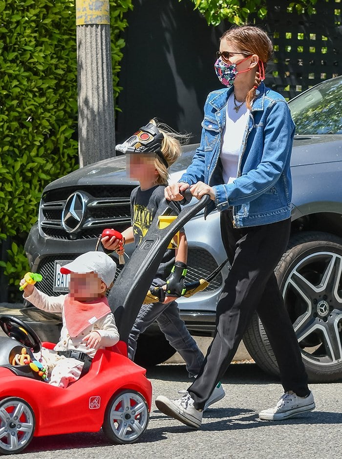 Kate wears a printed mask with a denim jacket, black pants, and Converse sneakers