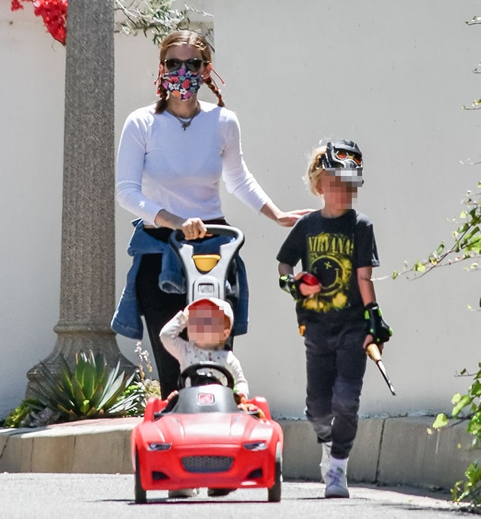 Kate Mara wraps her jacket around her waist as she pushes her daughter in a red car-shaped buggy