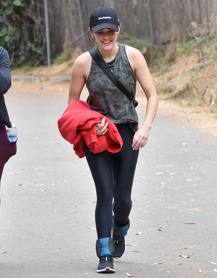 Lucy Hale wears a camo tank top with black leggings and Adidas shoes