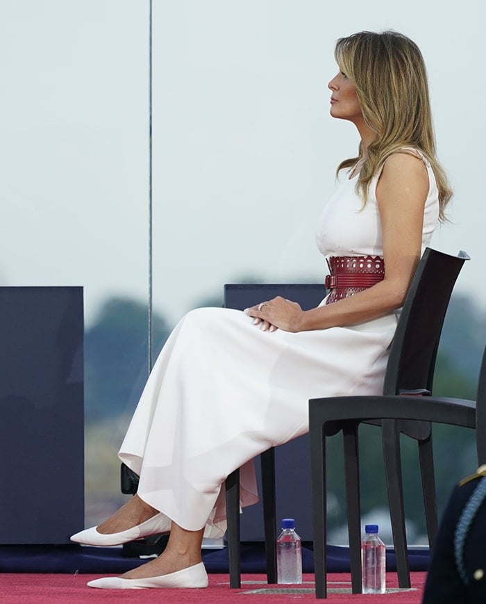Melania Trump wears a white tea-length dress with a wide Azzedine Alaia red belt