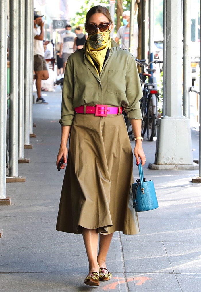 Olivia Palermo wears an earth-tone midi skirt and a loose shirt with a hot pink belt and yellow scarf