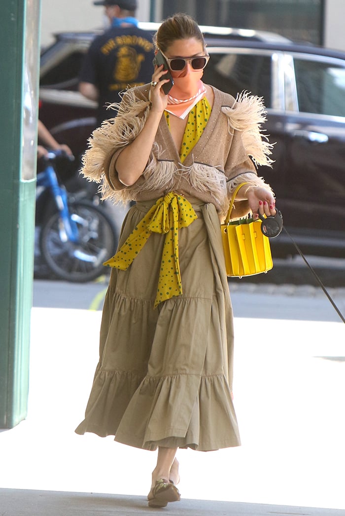 Olivia Palermo wears a khaki green tiered midi skirt with a yellow polka-dot blouse