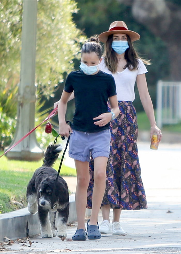 Ana de Armas channels boho-chic vibes in a printed Ulla Johnson midi skirt and white tee, accessorized with a Panama hat, as she walks with Ben Affleck's daughter, Seraphina, in casual shorts and Crocs