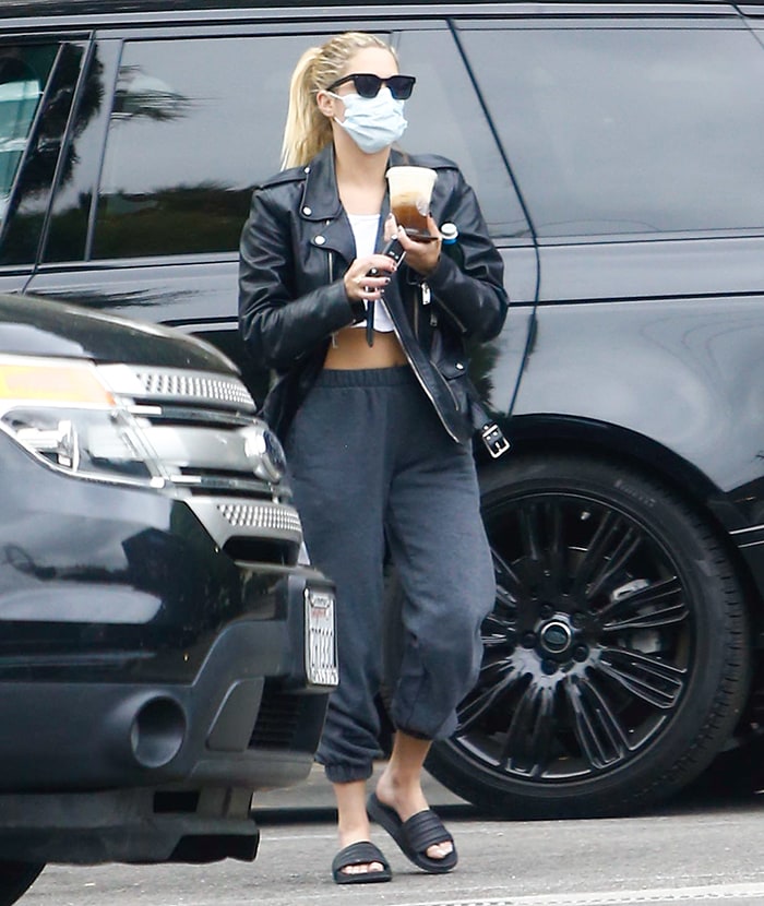 Ashley Benson teams her edgy jacket with a white crop top and black joggers