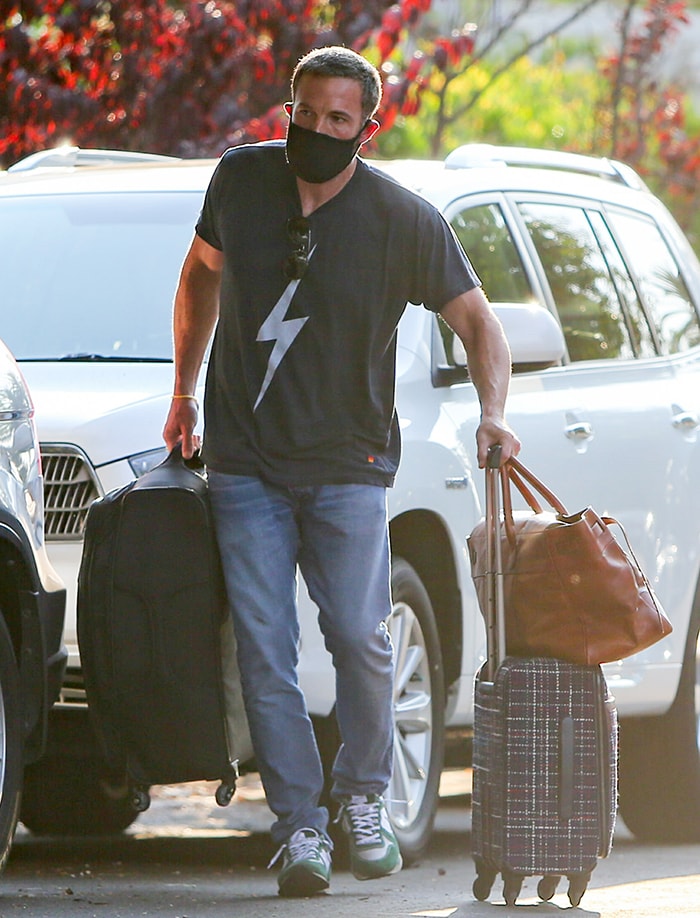 Ben Affleck keeps it casual in a lightning bolt tee and green sneakers while carrying luggage