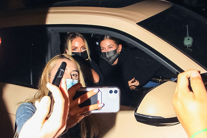 Hailey Bieber and her stylist Maeve Reilly pose for photos with a fan after a dinner date on September 21, 2020