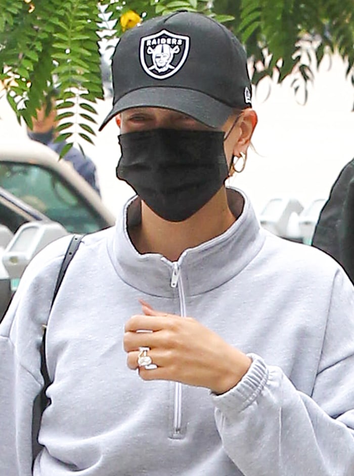 Hailey Bieber keeps a low profile with a baseball cap and a protective face mask