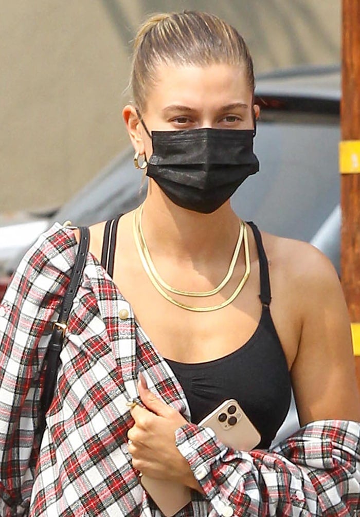 Hailey Bieber styles her hair in a bun and stays safe with a black face mask