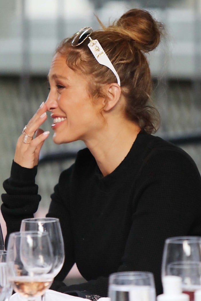 Jennifer Lopez wears her hair in a messy bun with her Versace sunglasses on her head