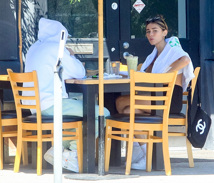 Madison Beer shows off her midriff in a white bra top and black biker shorts