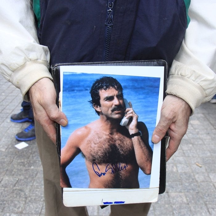 A fan holds a signed photo of Tom Selleck from his Magnum, P.I. days, showcasing his iconic beach look