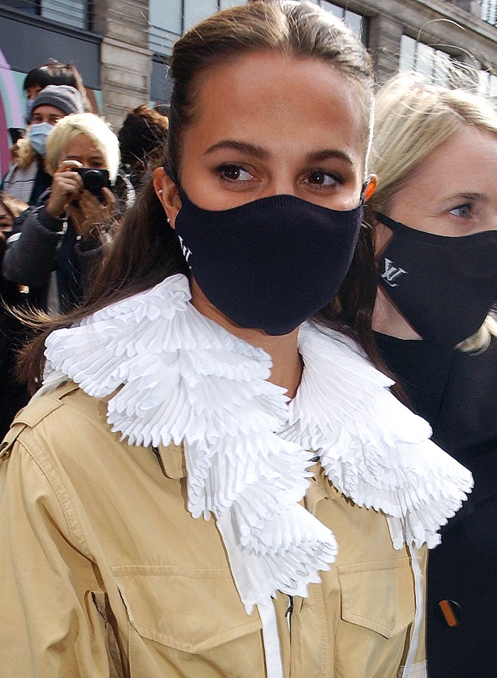 Alicia Vikander wears a Louis Vuitton Resort 2021 utility jacket with white ruffled collar and black face mask