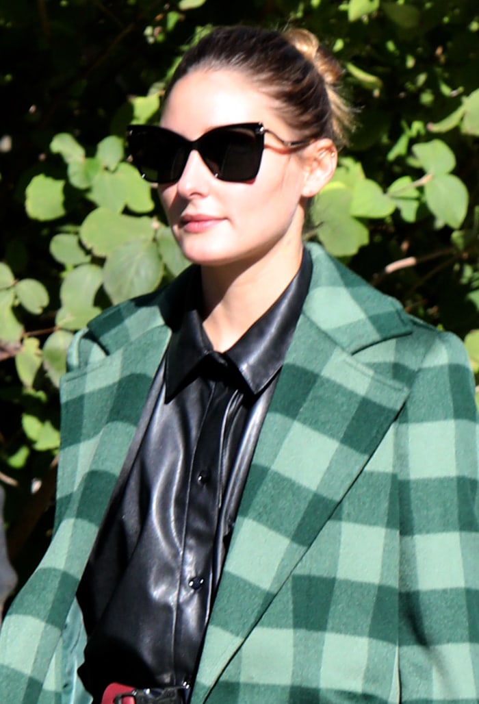 Olivia Palermo wears a bun hairstyle and shields her eyes behind a pair of angular sunglasses