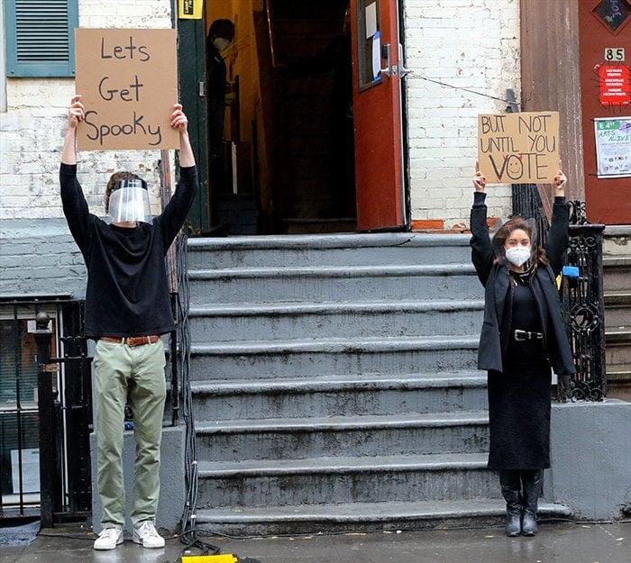 Seth Phillips, aka Dude with Sign, holds "Let's Get Spooky" placard while Vanessa Hudgens raises her "But not until you vote" sign