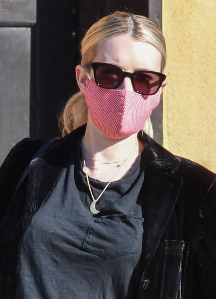 Emma Roberts pulls her blonde hair back into a ponytail and stays safe with a red face mask