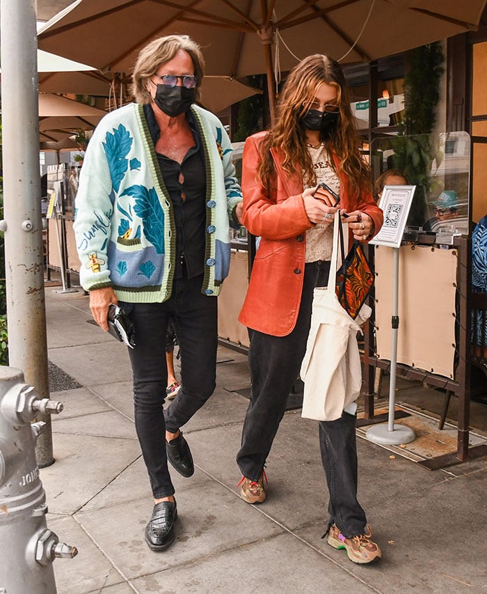 Mohamed Hadid wears a printed cardigan with black shirt and jeans while Bella dons a cream top with black baggy jeans