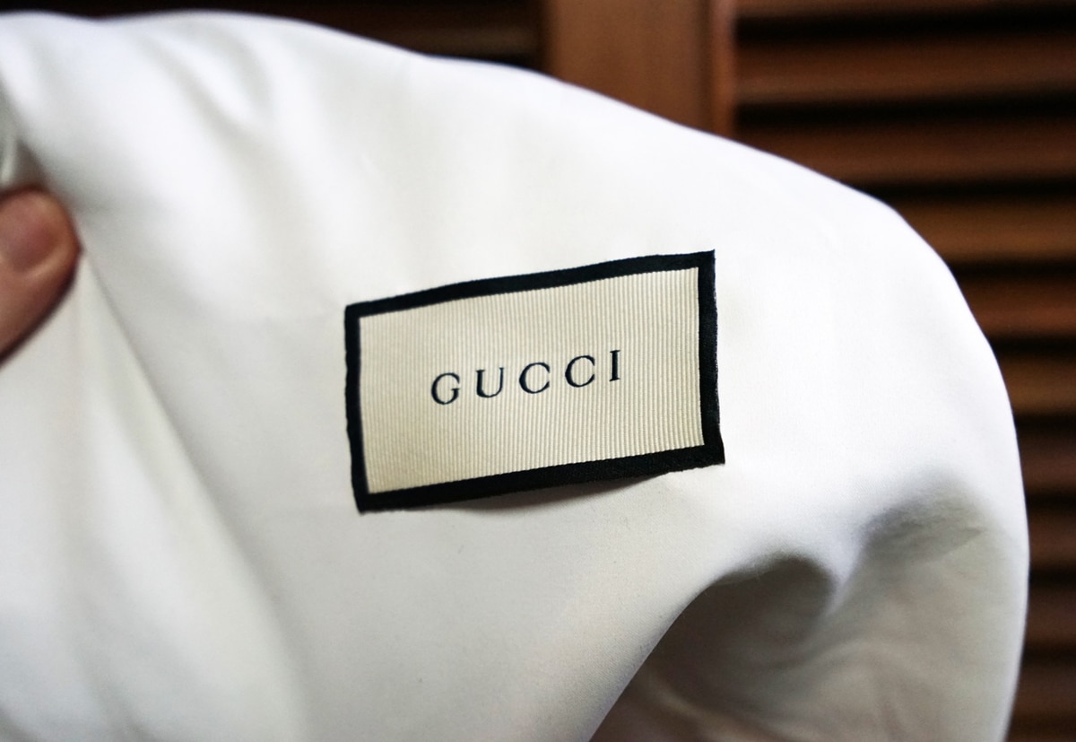 An authentic Gucci logo tag on a real white satin handbag dust cover