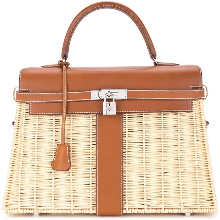 The Kelly picnic tote is crafted in France from beige and brown straw and leather and features leather trim, top handles, a front flap closure, a padlock fastening detail, a hanging key fob, and purse feet