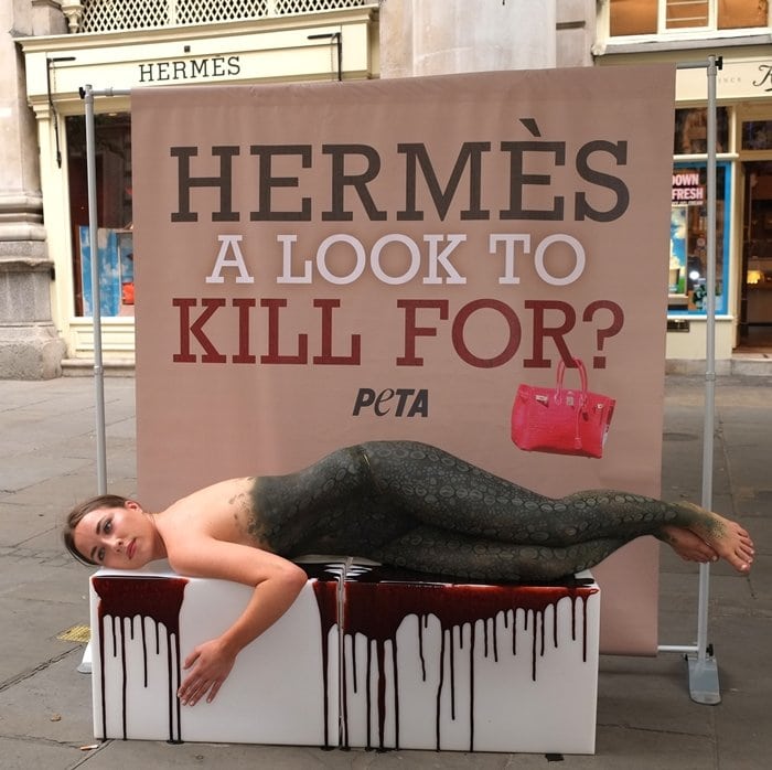A PETA supporter, painted to look like a crocodile lying in a pool of blood, lays outside the London Hermes store at The Royal Exchange in protest to the luxury brand's cruelty to reptiles