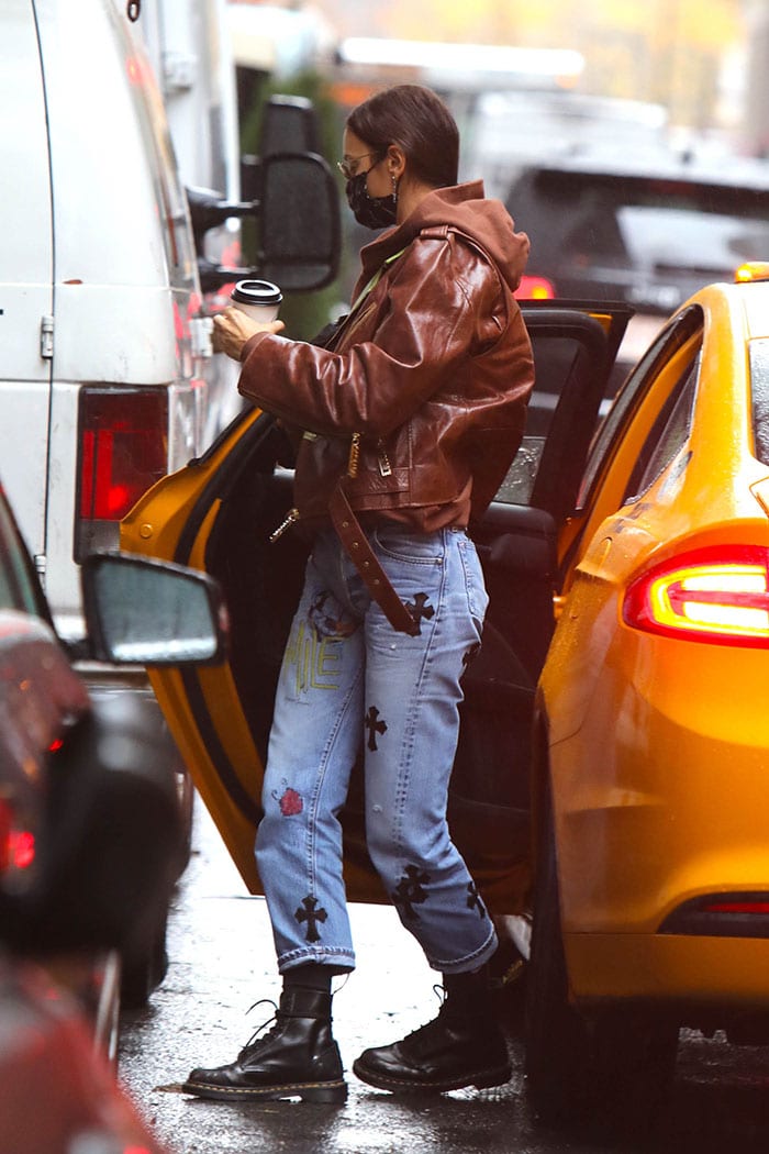 Irina Shayk bundles up in a brown leather jacket with brown hooded sweater and Chrome Hearts jeans