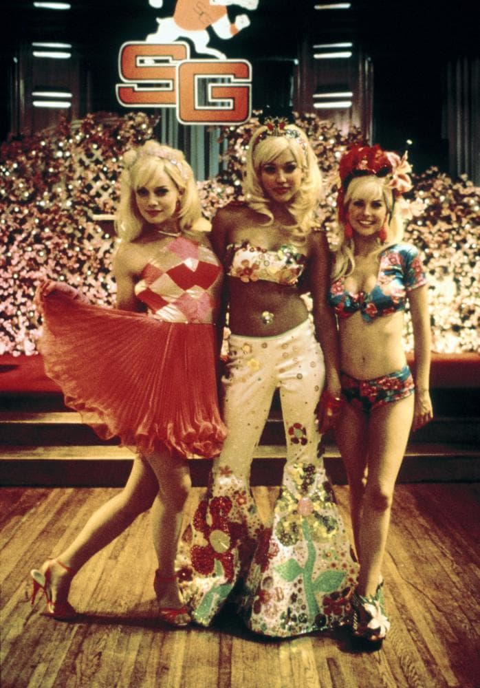 This still from the 1999 movie Never Been Kissed shows Jessica Alba, Jordan Ladd, and Marley Shelton in their vibrant Barbie-themed prom costumes, with Alba in a floral-inspired outfit and strappy sandals, while Ladd and Shelton complete their looks with playful footwear matching their costumes