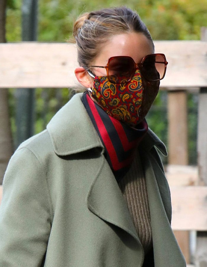 Olivia Palermo keeps it chic with a paisley facemask, rectangular sunglasses, and a red-and-navy scarf